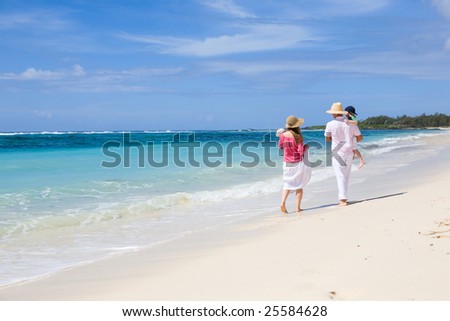 Family vacation. Young family of four walking along white sand tropical beach