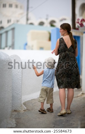 Family trip to Europe. Young mother with two kids exploring Greek town.