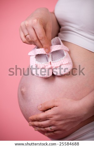 pink pregnant belly. stock photo : Pretty small pink shoes and pregnant belly