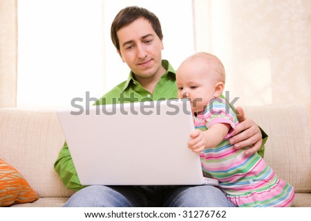 Father working on laptop from home while babysitting his daughter