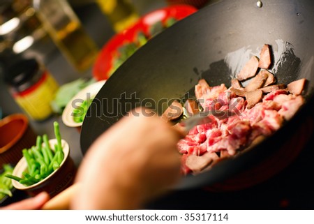 Chef cooking vegetables and meat in wok pan
