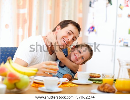 Young happy father and son having breakfast together