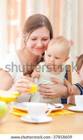 Young happy mother and baby daughter having breakfast together