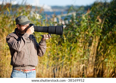 Young nature photographer with taking photos using telephoto lens