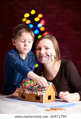 Family decorating gingerbread house at Christmas eve