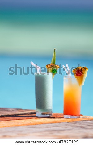 Two tropical cocktails near swimming pool and beach