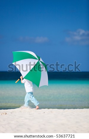Cute 5 years old boy with big umbrella on tropical beach