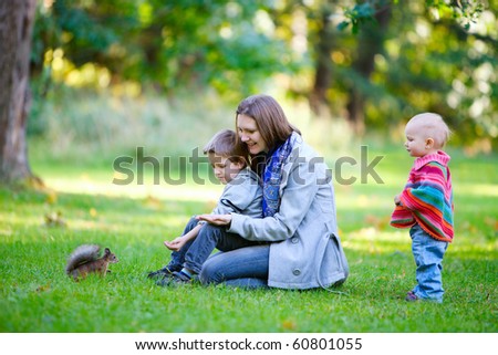 Family of three and little squirrel in autumn park