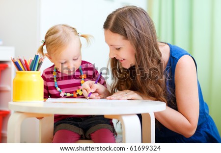 Young mother and her little daughter drawing together
