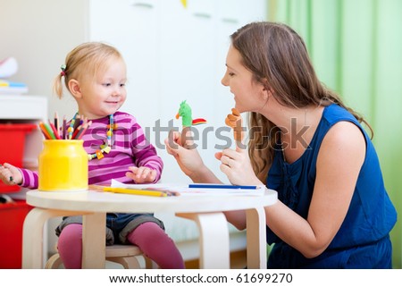 Young mother and her toddler girl playing together with finger toys