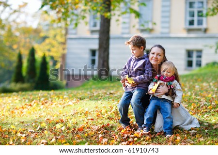 Mother and kids sitting outdoors at beautiful autumn park
