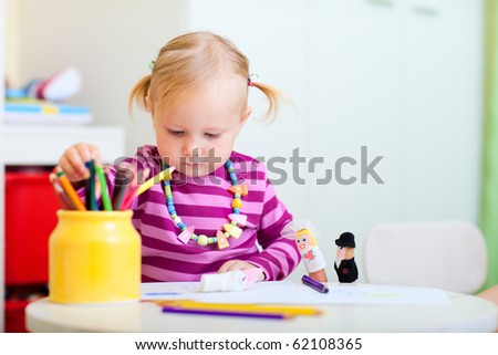 Portrait of adorable toddler girl coloring with pencils