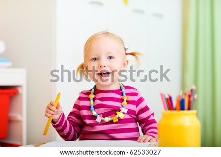 Adorable happy toddler girl drawing, perfect for early education context