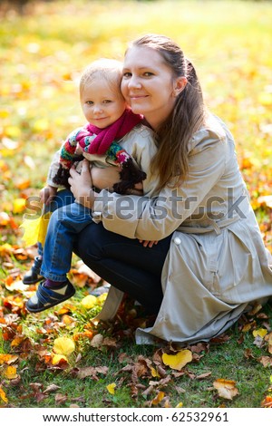 Portrait of young mother and her little daughter outdoors on sunny autumn day