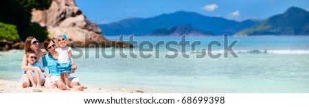 Panoramic photo of young family with two kids sitting on tropical beach
