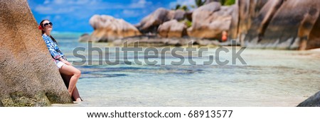 Panoramic photo of young beautiful woman at Anse Source d?Argent beach in Seychelles