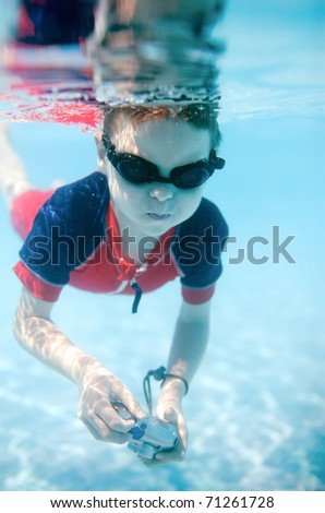 Cute 6 years old boy swimming underwater and making photos