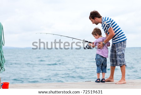 Young father and his son fishing together from wooden jetty