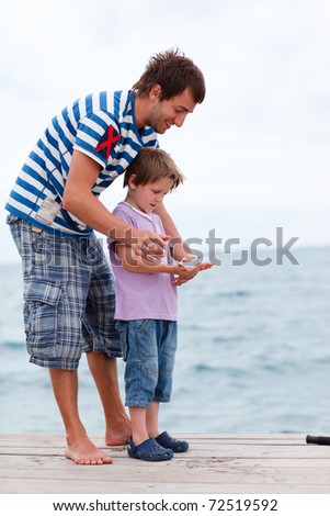 Father and son fishing from pier caught fish