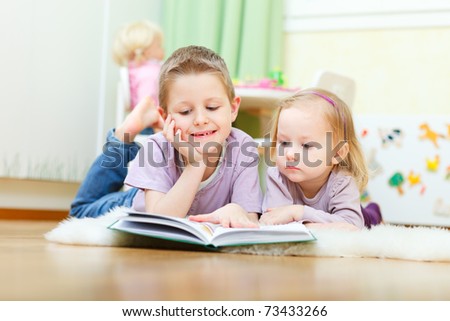 Brother and his little sister at home reading