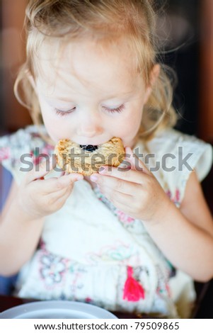 Portrait of adorable little girl eating cookie