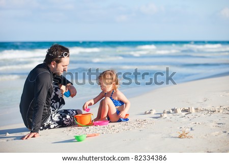 Father and daughter playing with toys at beach