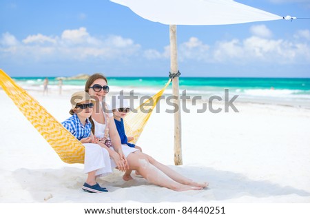 Mother and two kids sitting on hammock at tropical beach