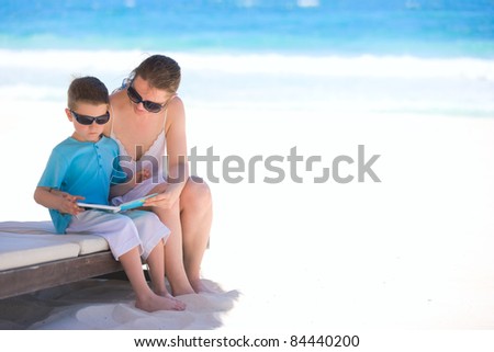 Mother and son reading book at tropical beach