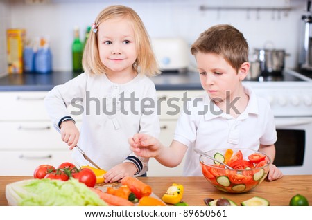 Two little kids helping at kitchen with salad making