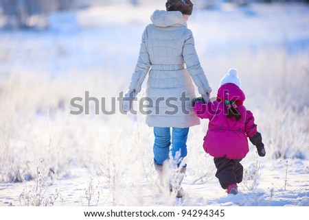 Back view of mother and daughter walking on winter day