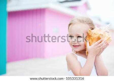 Adorable little girl with conch shell at colorful Caribbean village