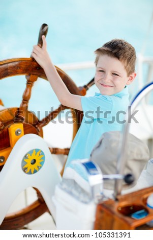 Cute little boy at sail boat wheel