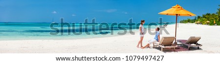 Romantic couple on a tropical beach during honeymoon vacation, wide panorama perfect for banners