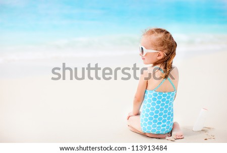 Little girl at beach with sun shaped cream at her shoulder