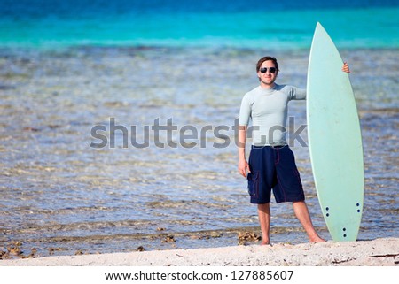 Young man with surfboard at tropical beach