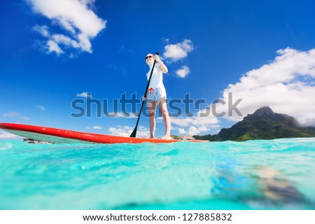 Active young woman on stand up paddle board