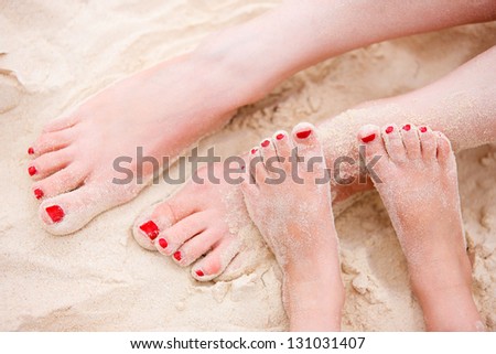 Close up of mother and daughter feet on a tropical sandy beach