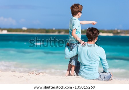 Back view of father and son on beach vacation