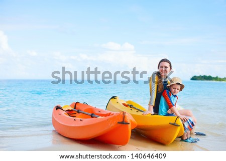 Happy mother and son with kayaks at tropical beach