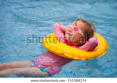 Adorable little girl with inflatable ring at swimming pool