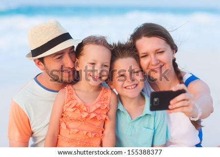 Beautiful family at beach making a self portrait with a mobile phone