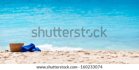 Panorama of a tropical beach with straw bag and towel on a sand