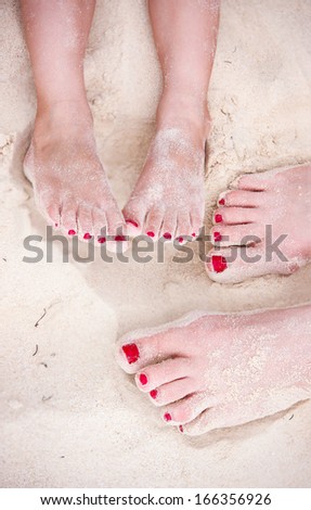 Close up of mother and daughter feet on a tropical sandy beach