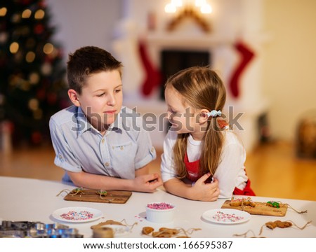 Two kids at home decorating freshly baked Christmas cookies