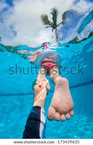 Father holding his little daughter feet while she swims