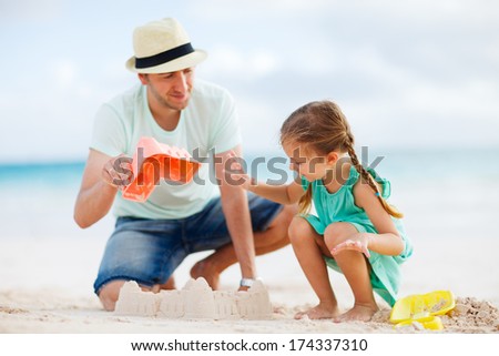 Father And Daughter On Beach Building Sand Castle
