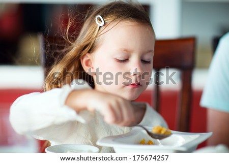 Adorable little girl eating breakfast in restaurant