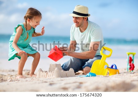 Father and daughter on beach building sand castle