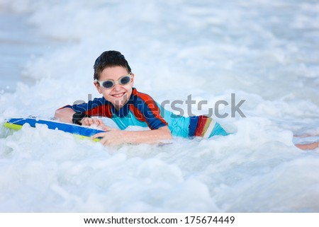 Little boy on vacation having fun swimming on boogie board