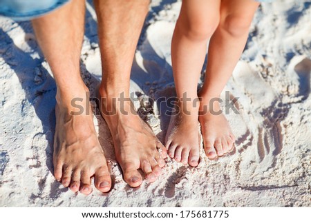 Close up of father and daughter feet on a tropical sandy beach